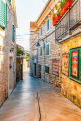 Naklejka premium Scenic coastal promenade and the old stone town of Primosten under a clear blue sky, Dalmatia, Croatia.