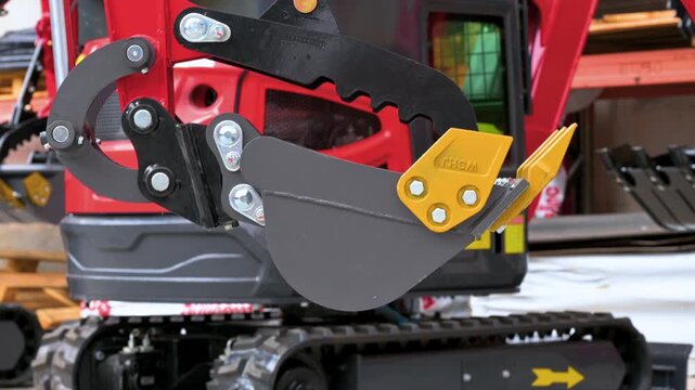Close-up of a mini excavator digging bucket and mechanical grapple thumb attachment. Heavy construction machinery and industrial tools. High quality 4k footage
