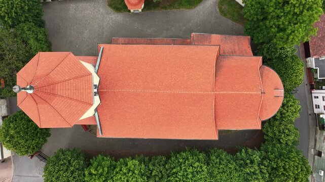 Aerial view of historic Przemkow in Lower Silesia, Poland with medieval town center, Baroque church, colorful buildings with clay tile roofs, surrounding green forests and landscape on sunny day