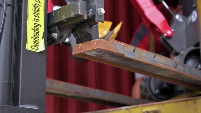 Detail view of a forklift lifting mechanism and steel fork with a prominent weight limit safety warning sign. Industrial material handling and warehouse logistics. High quality 4k footage