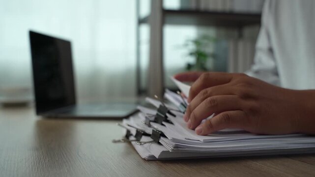 business man  sorting thick paper Document management system  on a wooden desk, showing an organized filing process for office records and document management workflow.