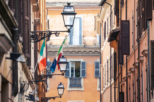 Street lamp and Italian flags between old facades, Rome, Italy