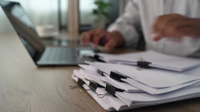 business man  sorting thick paper Document management system  on a wooden desk, showing an organized filing process for office records and document management workflow.