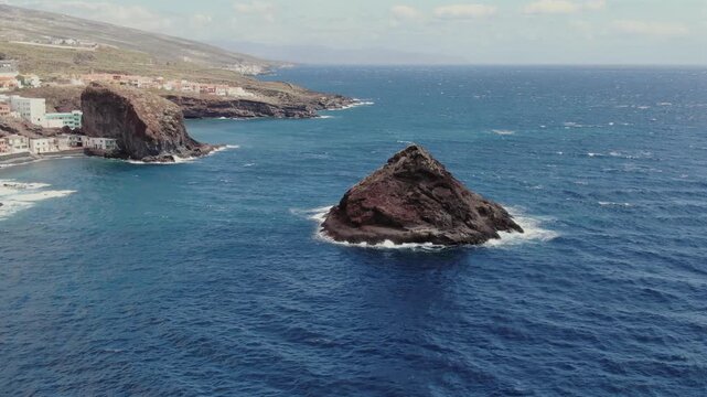 Majestic aerial view of the volcanic coastline of Tenerife with the village of Los Roques and the famous rocks emerging from the deep blue sea