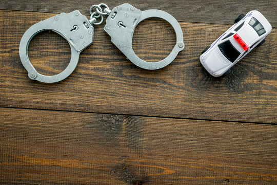 Police concept. Police car toy and handcuff on dark wooden background top view space for text