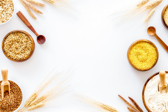 Healthy food. Cereals - rice, oats, buckwheat - in bowls with ears on white background top view frame copy space