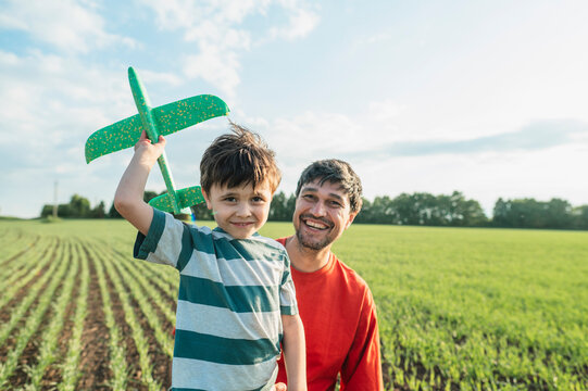 Father and son launching a toy airplane in the park