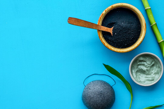 Face care. Cosmetics based on bamboo charcoal powder on blue background top view space for text