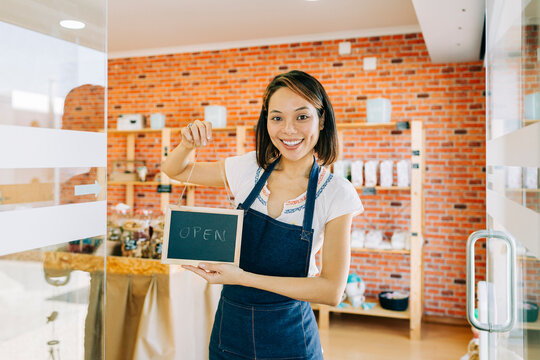 Smiling entrepreneur holding open sign in small business workplace