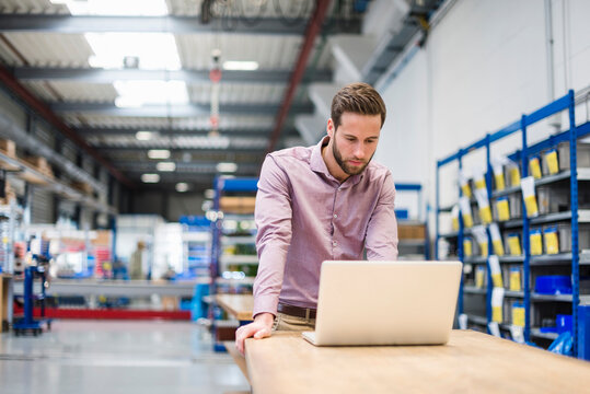 Young businessman using laptop in production hall