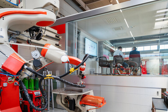 Men discuss business in a glass office near an industrial robot