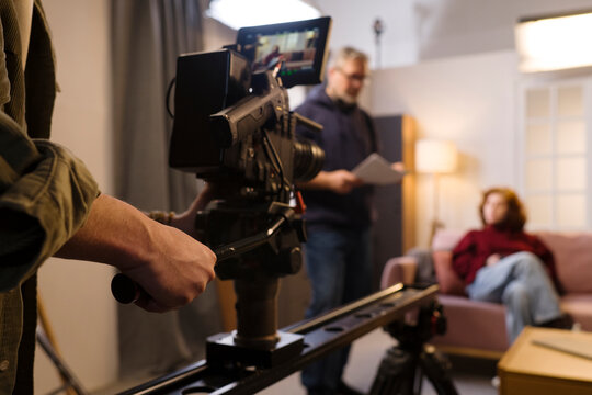 Camera operator films a woman on an indoor production set