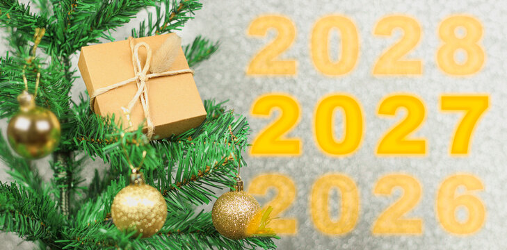 Happy New Year 2027 anniversary. Transition from 2026 to new year 2027 concept image with golden ball ornament on Christmas tree.