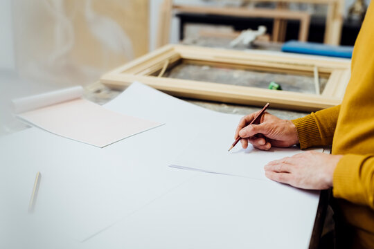 Craftsman drawing at workbench in workshop