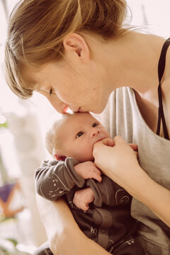 Mother testing newborn baby?s hunger with her finger and kissing its forehead