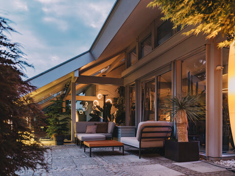 Modern timber frame villa with outdoor lounge seating at blue hour