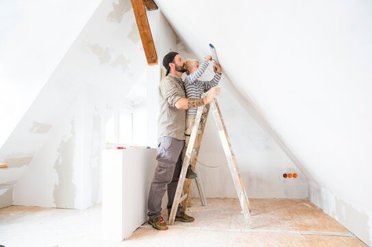 Father and son working on loft conversion using water level