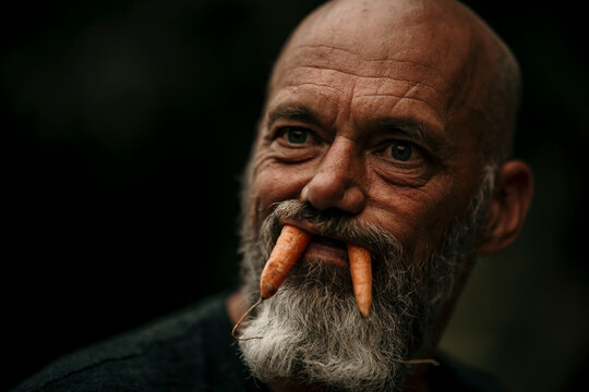Close-up of mature man with carrots in mouth