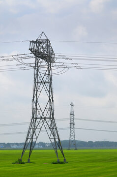 Electricity pylon stands in a green pasture in Groningen