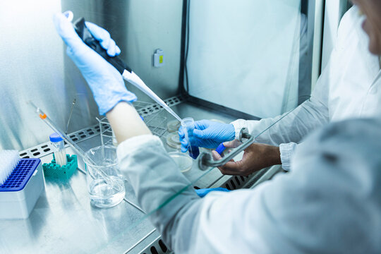 Scientist with colleague taking liquid solution with pipette
