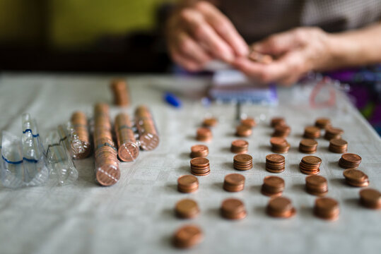 Elderly woman counting money, making stacks of Euro cents