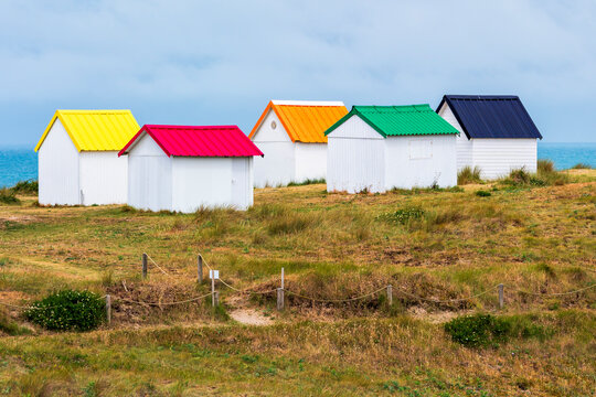 Colorful beach cabins stand on a grassy dune in Normandy France