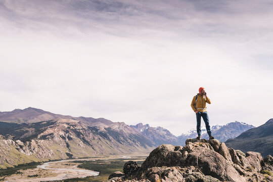 Mature man talking over smart phone while standing on rock against sky, Patagonia, Argentina