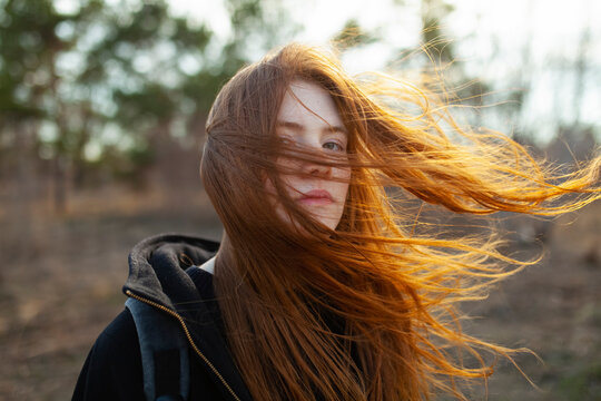 Portrait of teenage girl with red hair blowing in the wind on a sunny spring evening
