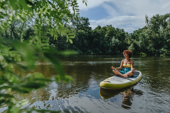 Woman meditating on paddleboard in lake