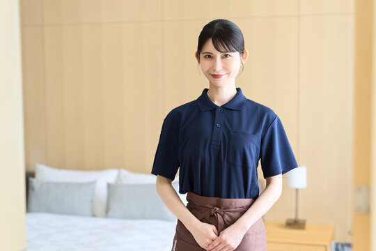 客室で笑顔で立つホテルの女性清掃員