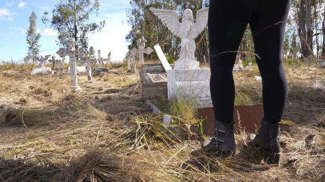 Grieving woman standing at a grave in an old cemetery expressing mourning and remembrance