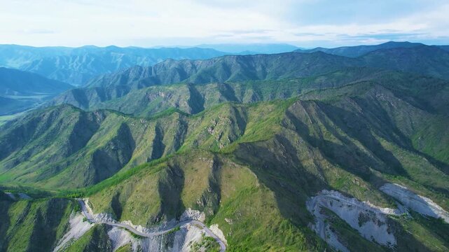 Aerial sunset panorama of rugged mountain ridge with winding switchback road along steep rocky slopes and distant peaks, with mountain, ridge, aerial, sunset detail