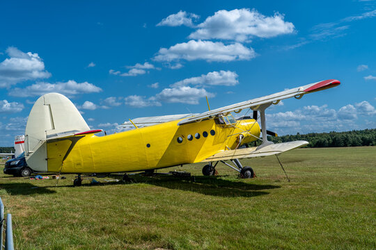 Yellow antonov an-2 biplane resting on a grassy field, ready for flight