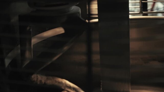 Rotating spiral mechanism movement within industrial mixer processing dough in large metal container. Private bakery production facility during bread making process. Production of baked goods