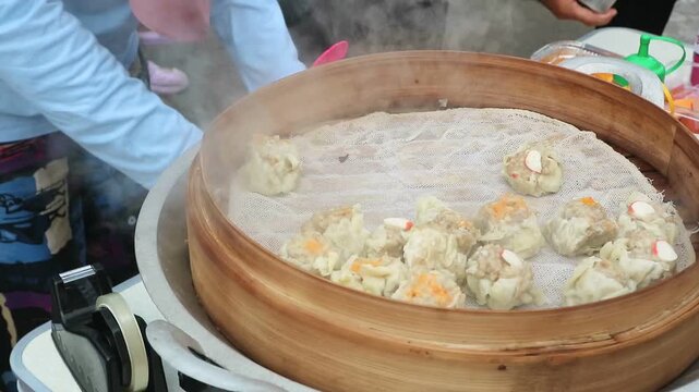 Hot steaming siomay dumplings cooking in a traditional bamboo steamer.