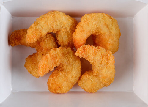 Crispy breaded shrimp in panko breading deep fried in white paper take out box top view extreme close up flat lay delicious seafood snack food