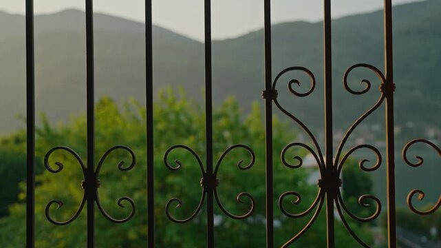 A close-up perspective through a traditional ornate Italian balcony, with a decorative balustrade in focus and a dreamy bokeh of lake and mountains in the background, evoking Mediterranean elegance.