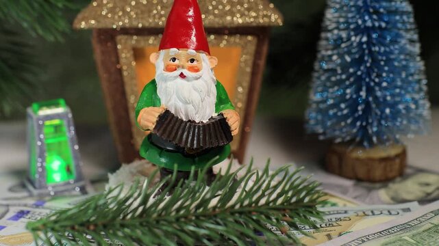 Close-up of a gnome with dollars and a Christmas tree branch against the background of a Christmas lantern