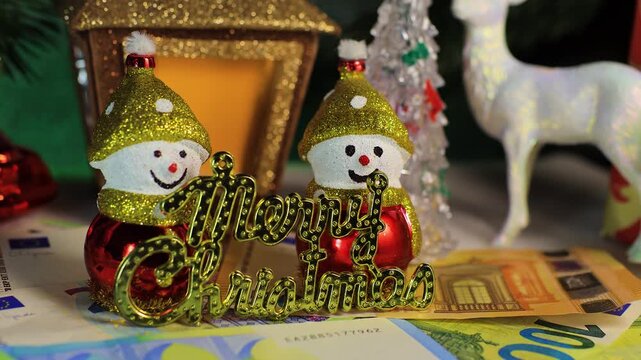 Snowmen with euro banknotes and letters near a Christmas lantern with fir trees