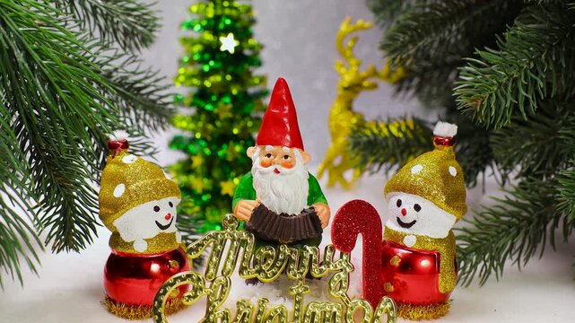 On a white surface among the Christmas trees there is a gnome with snowmen and letters