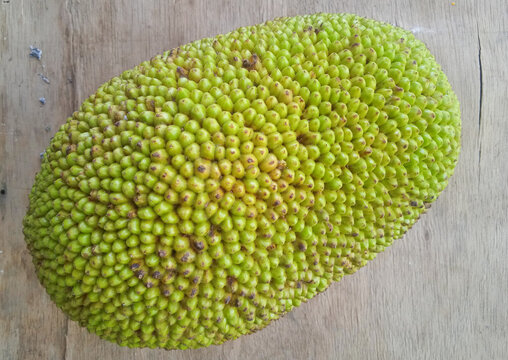 top view of a whole fresh green jackfruit on a wooden background