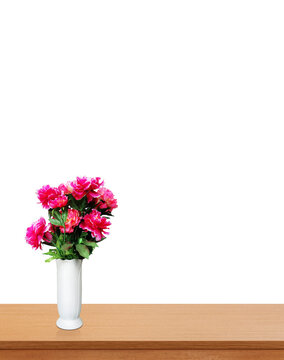 Red plastic flowers in a white vase, placed on a wooden table PNG transparent.