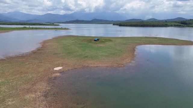 Drone footage captured flying along an exposed island at Song Hinh Lake in Dak Lak (formerly Phu Yen) Province, Vietnam. The aerial view documents a flat landform revealed by low water levels