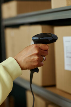 Vertical shot of middle aged worker scanning warehouse boxes with barcode reader, managing inventory and order tracking. Useful for logistics, retail operations, supply chain marketing