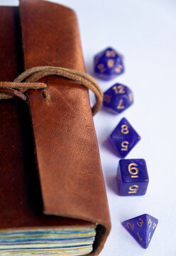Purple polyhedral dice set and fantasy miniature figurine next to a leather journal, close-up shot