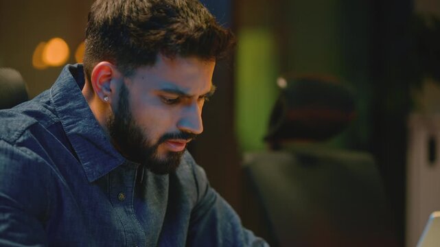 Pensive stressed irritated Indian business man angry with laptop difficult work at night office tired Arabian businessman Hindu male suffer with computer losing error problem at dark evening company