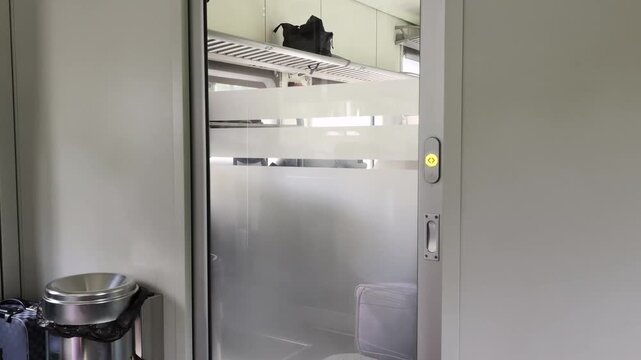 Frosted glass sliding door to a modern train compartment showing a glimpse of interior luggage rack and passenger area, sleek design of a railway cabin access, empty transit space