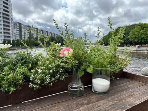 Fresh flowers and glass of milk on wooden table by riverbank  