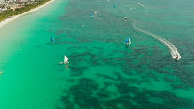 Sandy beach and turquoise water in the tropical resort of Boracay, Philippines. White beach with tourists and hotels. Summer and travel vacation concept.