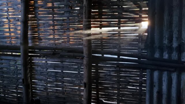Dramatic sunbeams shining through old wooden shack wall with cinematic smoke mist